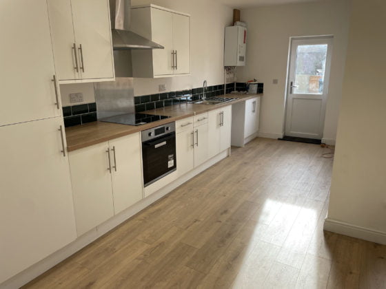 Modern kitchen interior with wooden worktops and white cabinets.
