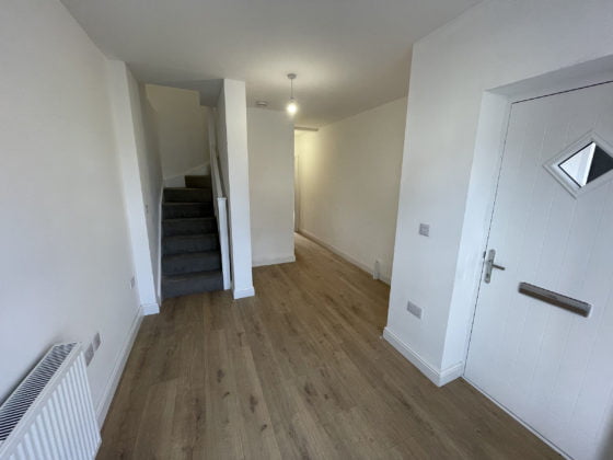 Spacious hallway interior with staircase and wooden flooring.