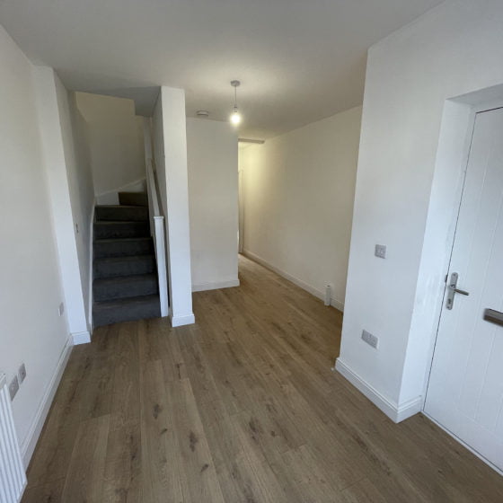 Spacious hallway interior with staircase and wooden flooring.