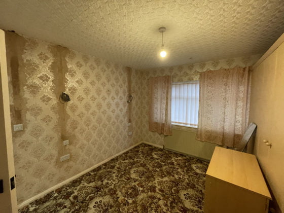 Empty vintage room with patterned wallpaper and carpet.