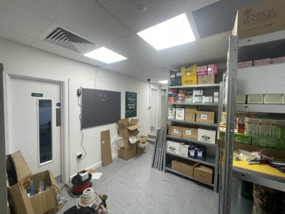 Cluttered storeroom with shelves, boxes, and tools.