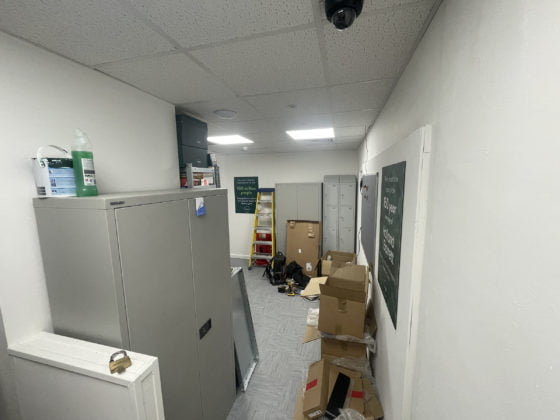 Office corridor with storage cabinets and cluttered boxes.