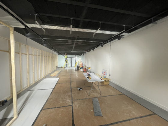 Interior construction site with worker on ladder.