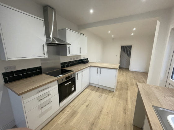 Modern kitchen interior with wooden worktops and white cabinets.