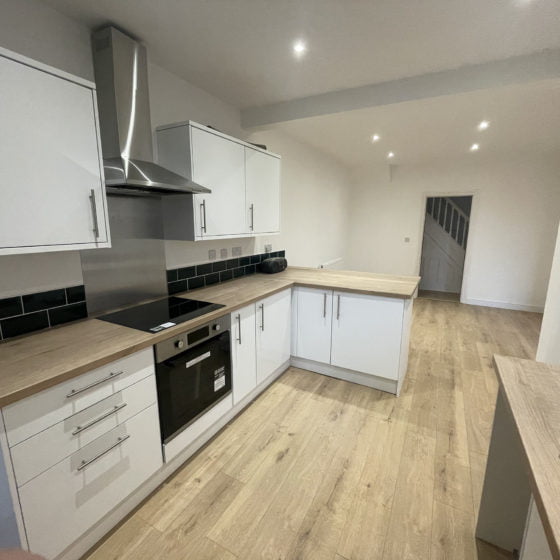 Modern kitchen interior with wooden worktops and white cabinets.