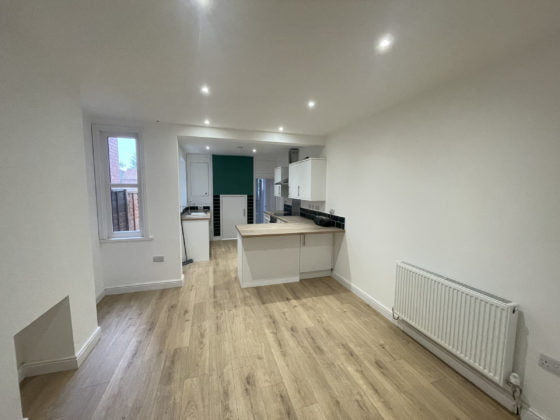Modern kitchen interior with wooden floors and white cabinets.