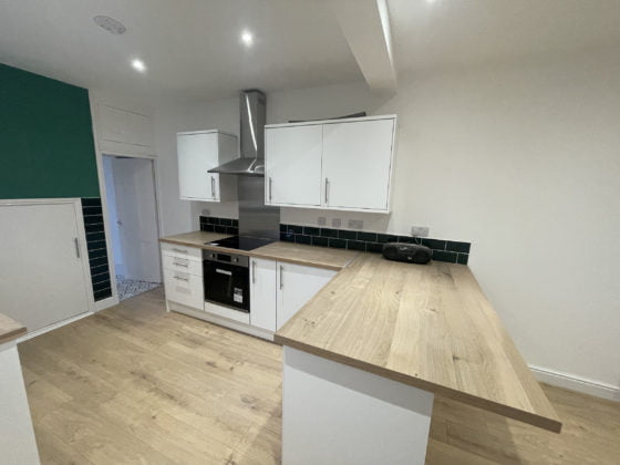 Modern kitchen with white cabinets and wood countertops.