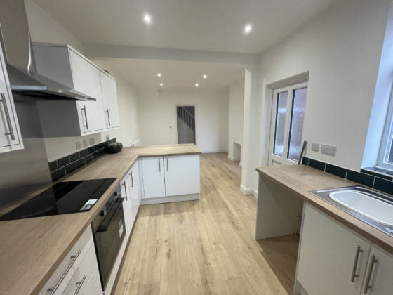 Modern kitchen with white cabinets and wooden floor.