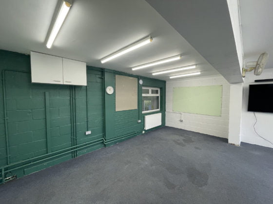 Empty room with fluorescent lights and green walls.
