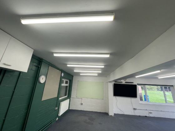 Classroom with fluorescent lights, clock, and mounted TV.
