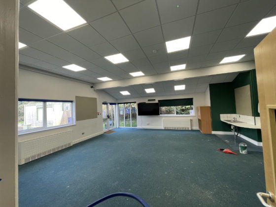 Modern classroom interior with interactive whiteboard and lights.