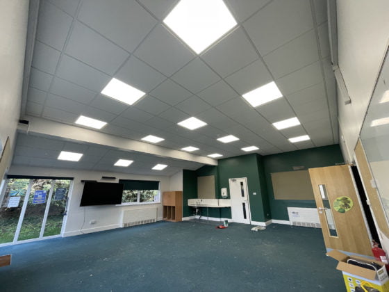 Empty classroom with illuminated ceiling panels.