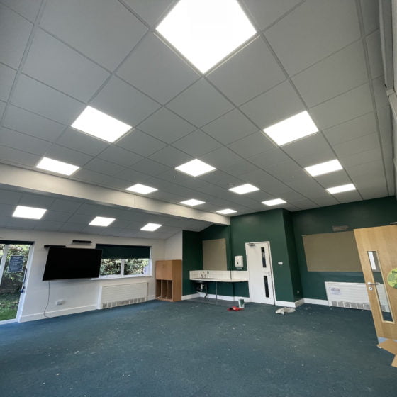 Empty classroom with illuminated ceiling panels.