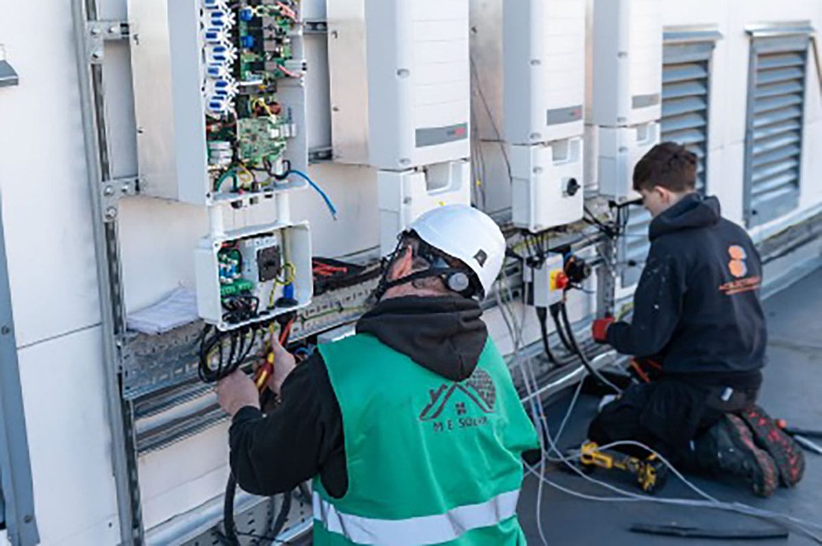 Technicians working on electrical equipment outdoors.