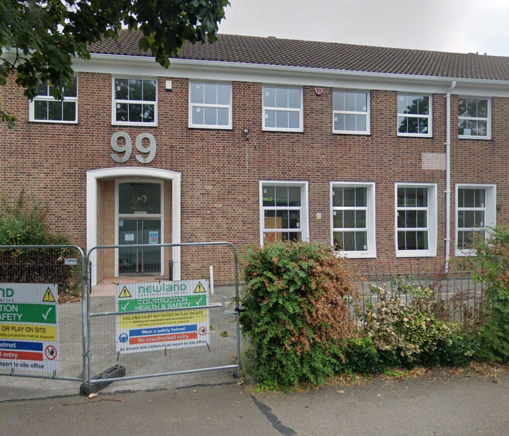 Brick building with number 99 and safety signs.